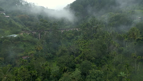 distant rising establishing aerial drone shot of nine arches bridge on misty morning in ella sri lanka