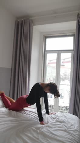 mujer haciendo yoga en una cama en un dormitorio
