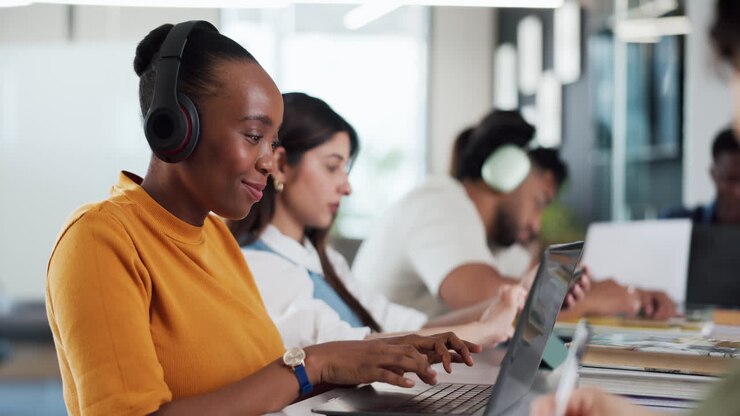 Young Woman in Headphones Working on Laptop in Modern Office