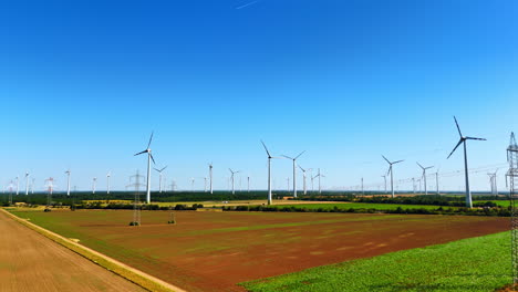 turbines produce clean power. vast fields stretch under a clear blue sky, dotted with wind turbines harnessing renewable energy