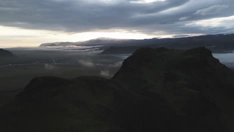 drone crane over dark vik mountain reveal foggy iceland plateau in vivid sunset