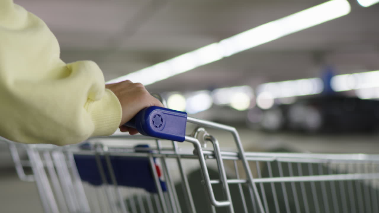 Close-Up of Hand Pushing Shopping Cart in Underground Parking