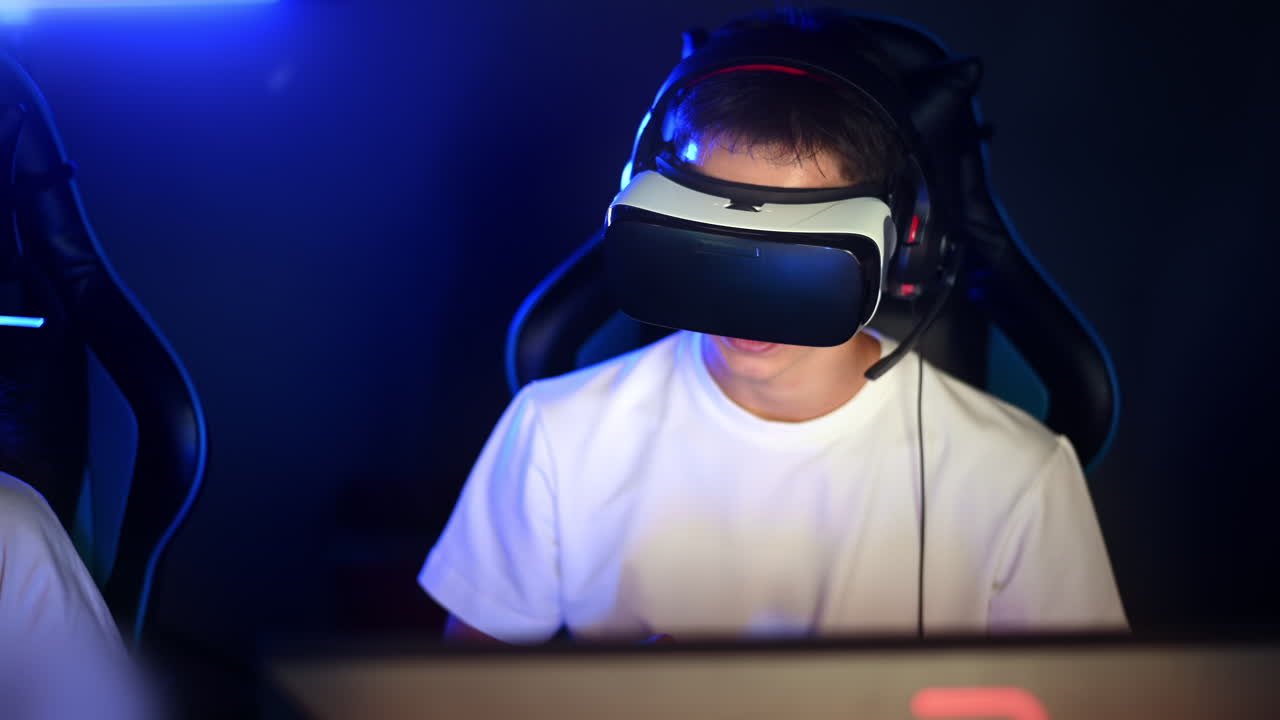Teenagere, hvid dreng og sort pige, med VR-headset spiller videospil i en videospilsklub med blå belysning