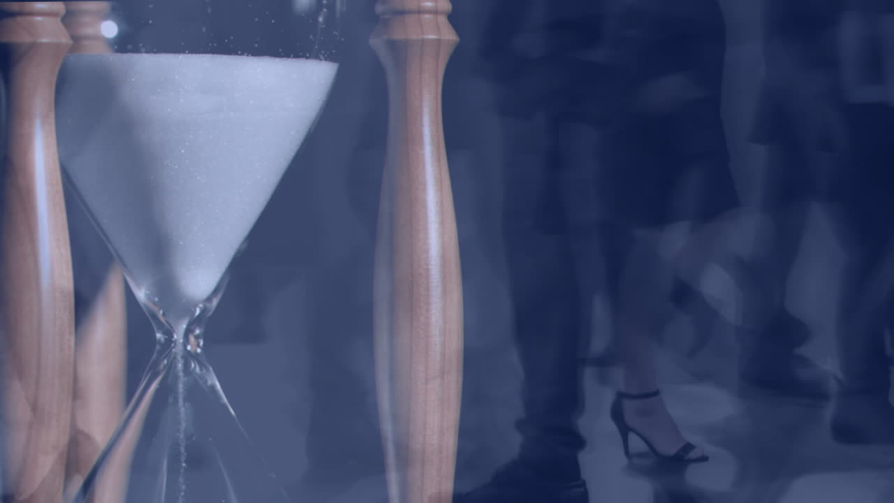 People walking fast with hourglass in the foreground