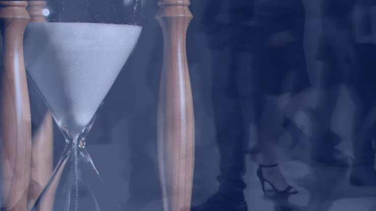 People walking fast with hourglass in the foreground