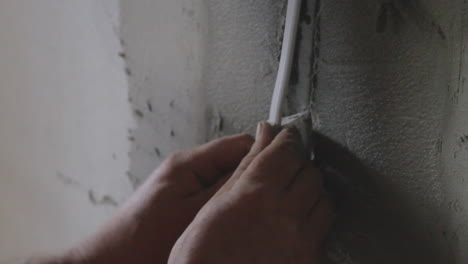 a worker is placing an electric cable on a wall