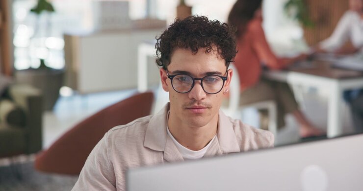 Ung mand arbejder på computer i moderne kontor