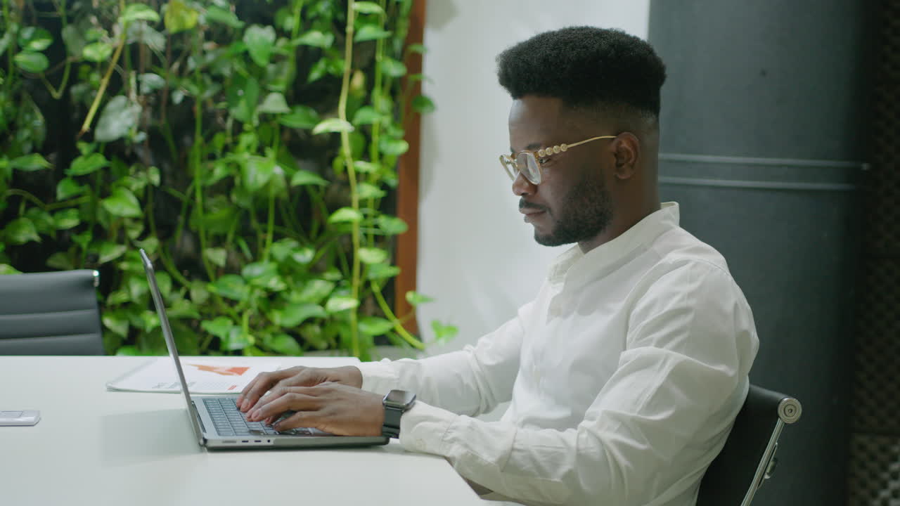 Businessman Using Laptop in Coworking Office with Green Wall
