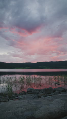 a vertical shot of a lake at sunset, with pink and blue clouds reflecting on water.