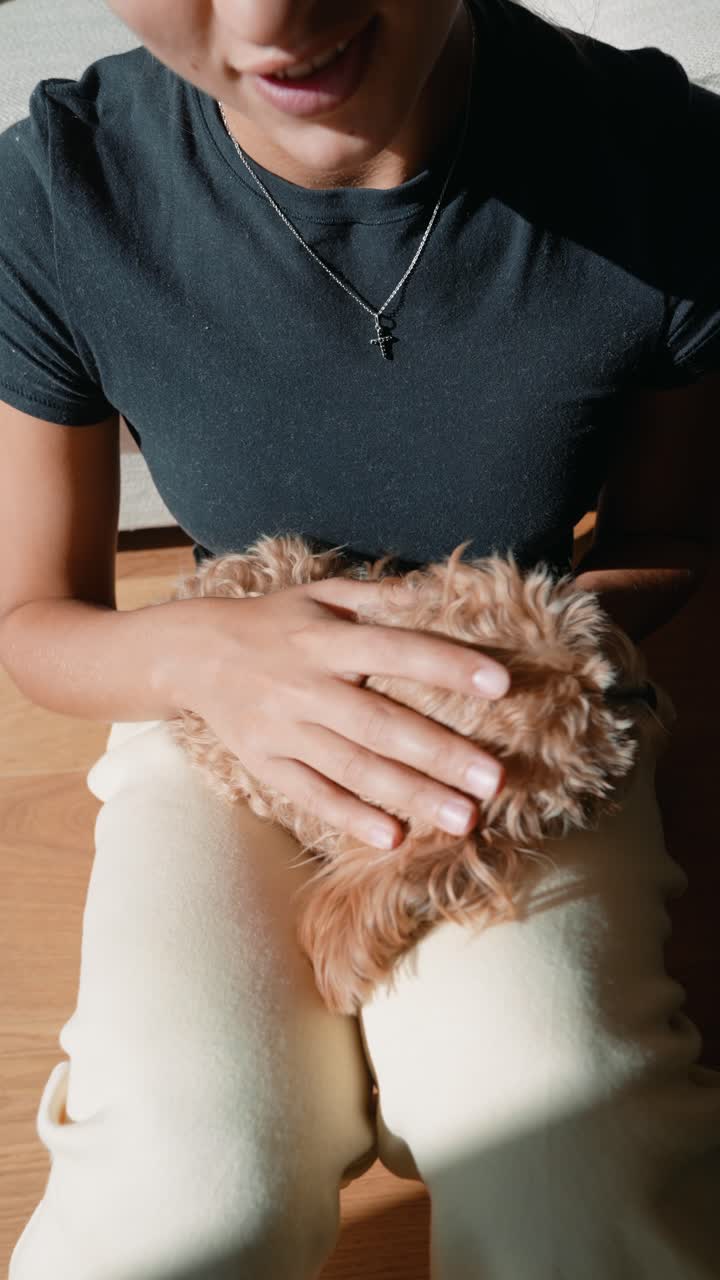Donna che accarezza e coccola il suo cagnolino sul pavimento