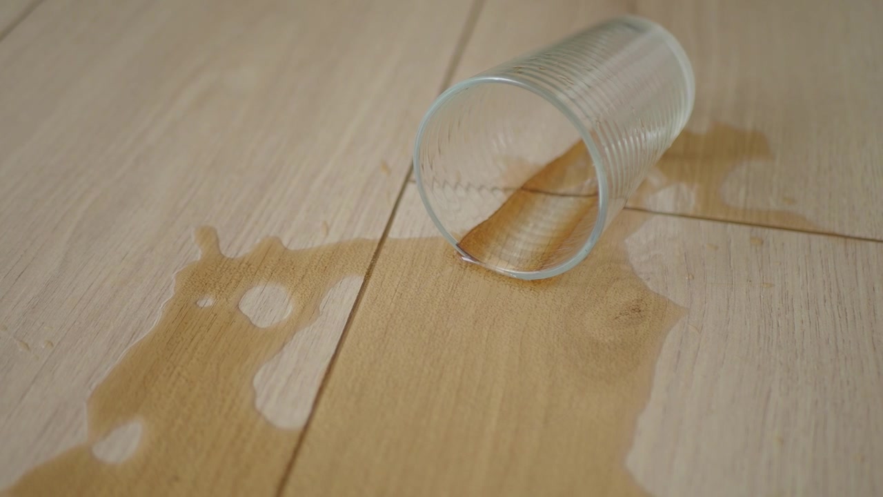 Spilt glass med vann på tregulv
