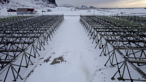 wooden dry fish rack, stativ at hovden beach in scandinavia, close up flyover aerial shot 4k