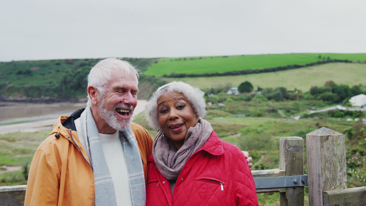 retrato de una pareja de ancianos activos caminando por un sendero costero en otoño o invierno