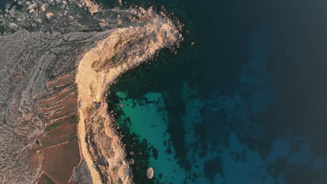 sunset drone footage capturing the seaside cliffs and crystal clear water on the coastline of malta