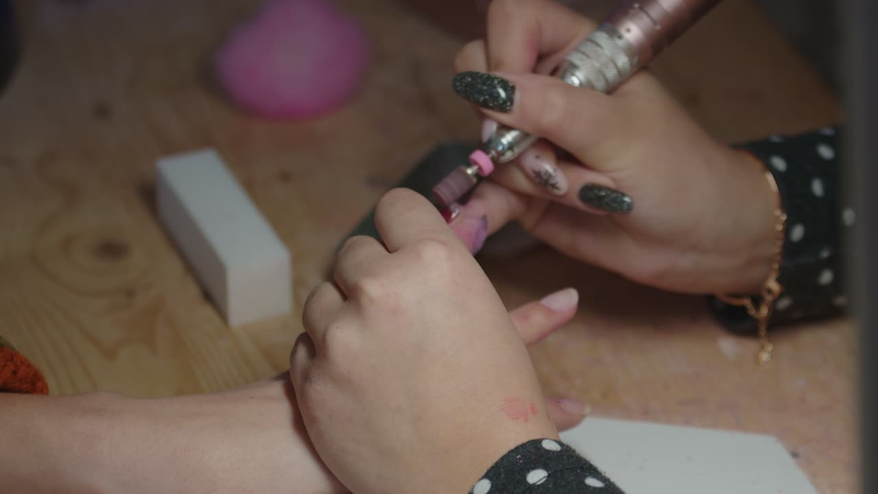 mujer manicurista quitando el esmalte de uñas de las uñas con una herramienta eléctrica de lijado