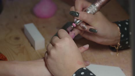 mujer manicurista quitando el esmalte de uñas de las uñas con una herramienta eléctrica de lijado