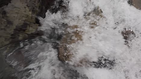 Zoom-in-to-glacier-and-flood-water-stream-through-rocky-river-bed,-Iceland