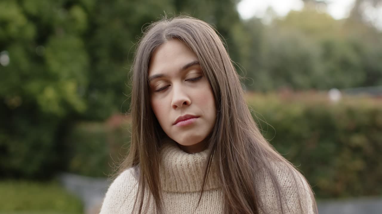 Woman reacting to opening frame by turning face toward camera, blinking, tilting head in garden
