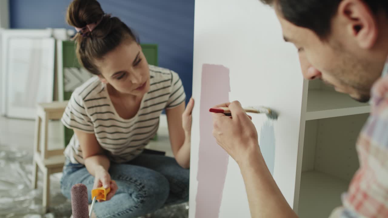 Tracking video of couple painting and choosing the right color.