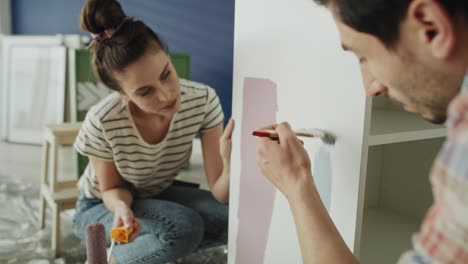 tracking video of couple painting and choosing the right color.