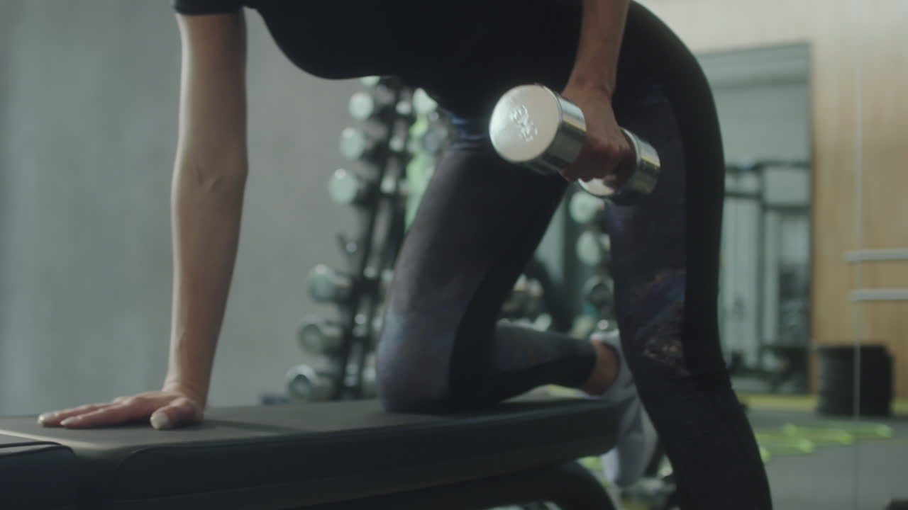 Woman Performing Dumbbell Exercise in Gym
