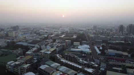 A-city-at-sunrise-with-soft-light-bathing-the-buildings-and-streets,-hinting-at-the-day's-beginning,-aerial-view