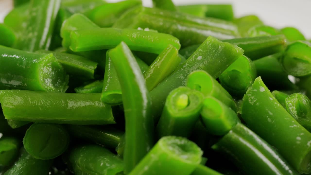 Fried wok green beans with onions and spices in a white plate on a gray background. Flat lay. Top view. High quality 4k footage