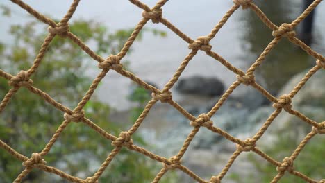 close up of rope net fence with blurred ocean in the background