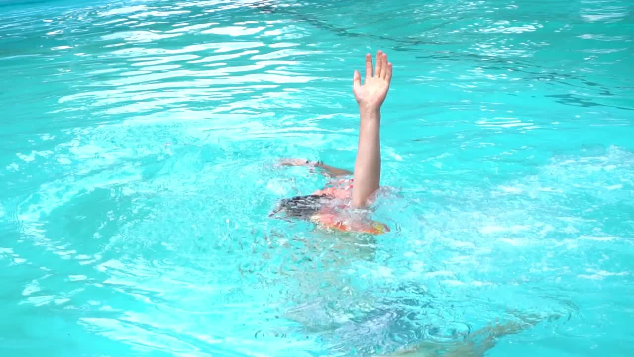 niño fingiendo ahogarse en una piscina con un chaleco salvavidas