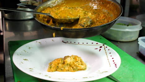 Chef-decorating-seafood-risotto-in-restaurant,-close-up,-Mediterranean