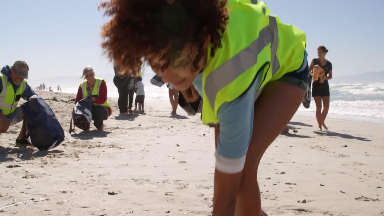 mujer voluntaria limpiando la playa en un día soleado 4k