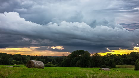 Dark-clouds-flying-over-agricultural-field-during-yellow-sunlight-hiding-at-horizon---time-lapse-shot