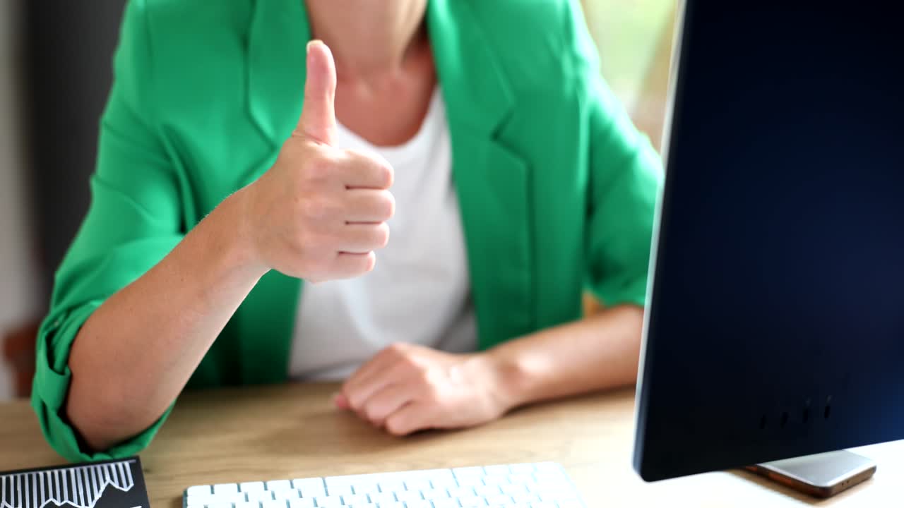 Woman giving thumbs up at desk