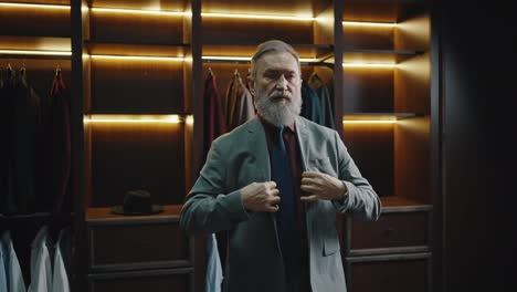 bearded mature businessman getting ready for work, putting on jacket at dressing room and going away, empty space