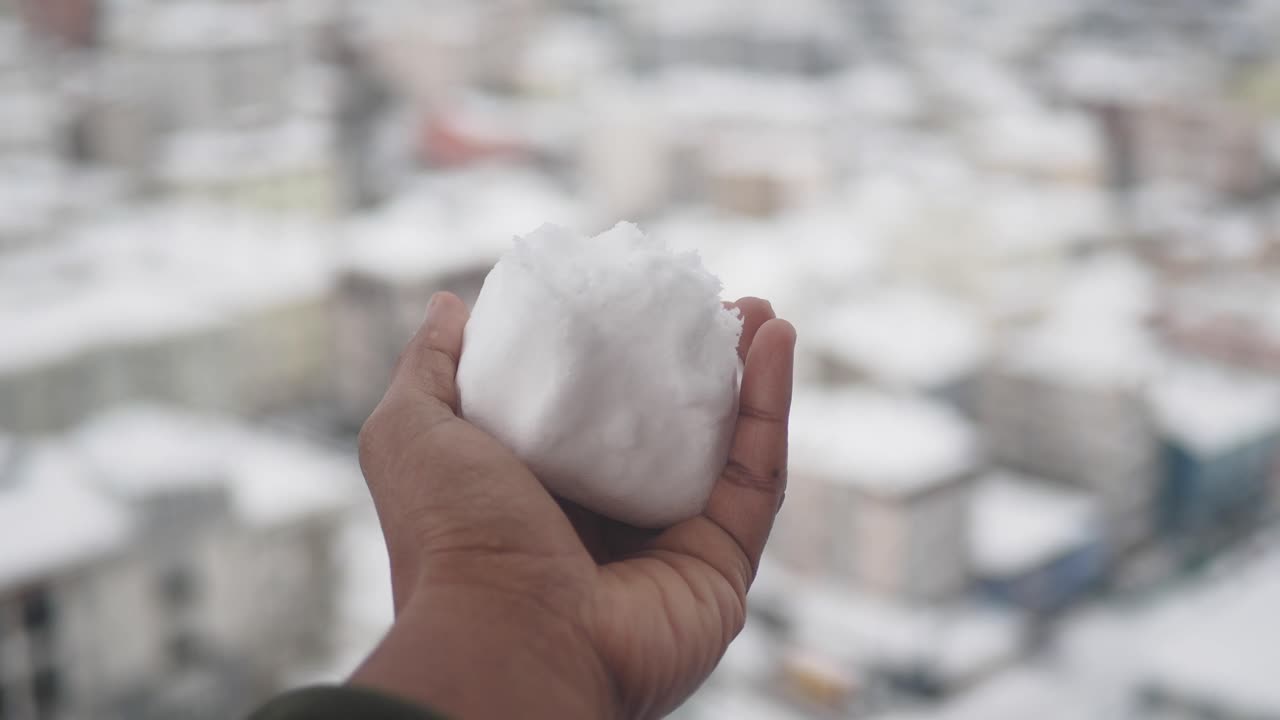 bola de nieve en la mano, vista de la ciudad nevada