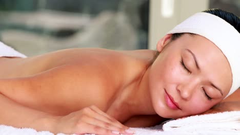 schöne brünette liegt mit geschlossenen augen auf dem massagetisch