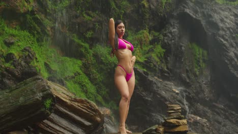 a young woman in a bikini stands where a waterfall tumbles gracefully on the island of trinidad.