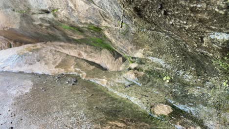 agua goteando de la formación rocosa cerca de las rocas con musgo y agua