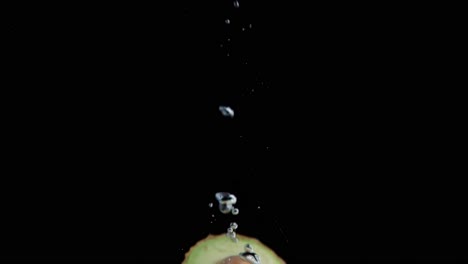 Avocado-Fällt-Ins-Wasser-Super-Slowmotion,-Schwarzer-Hintergrund,-Viele-Luftblasen,-4k240fps