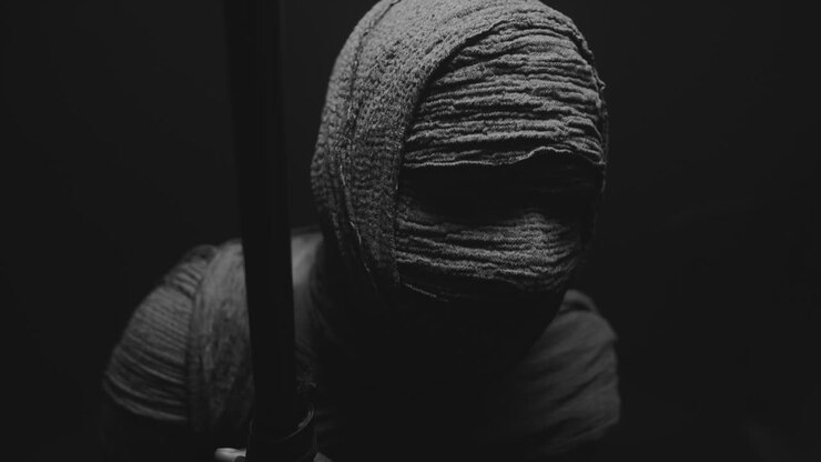 Una donna mummificata su uno sfondo scuro in posa con un bastone da passeggio.