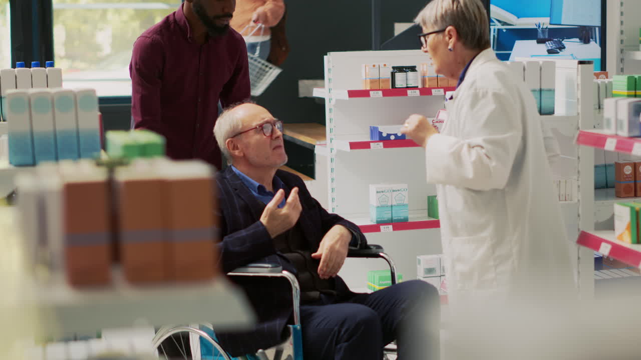 Senior Man in Wheelchair Consulting Pharmacist at Pharmacy