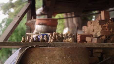 A-man-in-Thanh-Ha-pottery-village,-Vietnam,-takes-out-newly-crafted-clay-flute-animals-from-a-wooden-board,-showcasing-traditional-pottery-skills