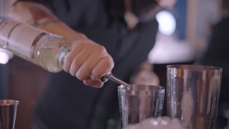 bartender pouring liquor into cocktail shaker