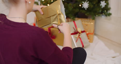 Woman-Wrapping-Christmas-Present-By-Fireplace-At-Home-11