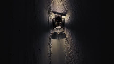 snow groomer at night in dolomites, alps, italy, illuminated path, winter maintenance, aerial view