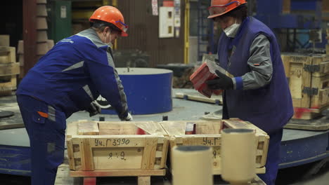 workers preparing metal casting molds in a factory