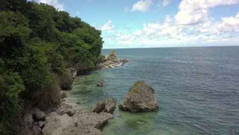 Amazing-low-flying-shot-forward-above-coast-rocks-on-beach-in-Bali,-lovely-turquoise-water,-tide-pools