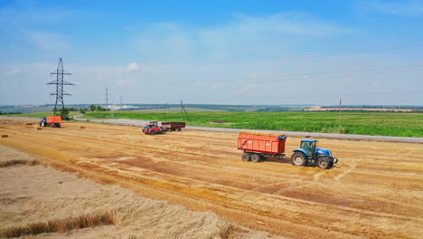 agricultural machine moving by the cut wheat field. tractor downloaded with hay bales rides by the plantation. high angle view.
