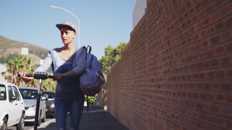 mujer de raza mixta caminando junto a su scooter eléctrico