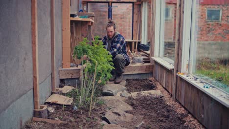 a man is planting inside the hothouse at the backyard. static shot